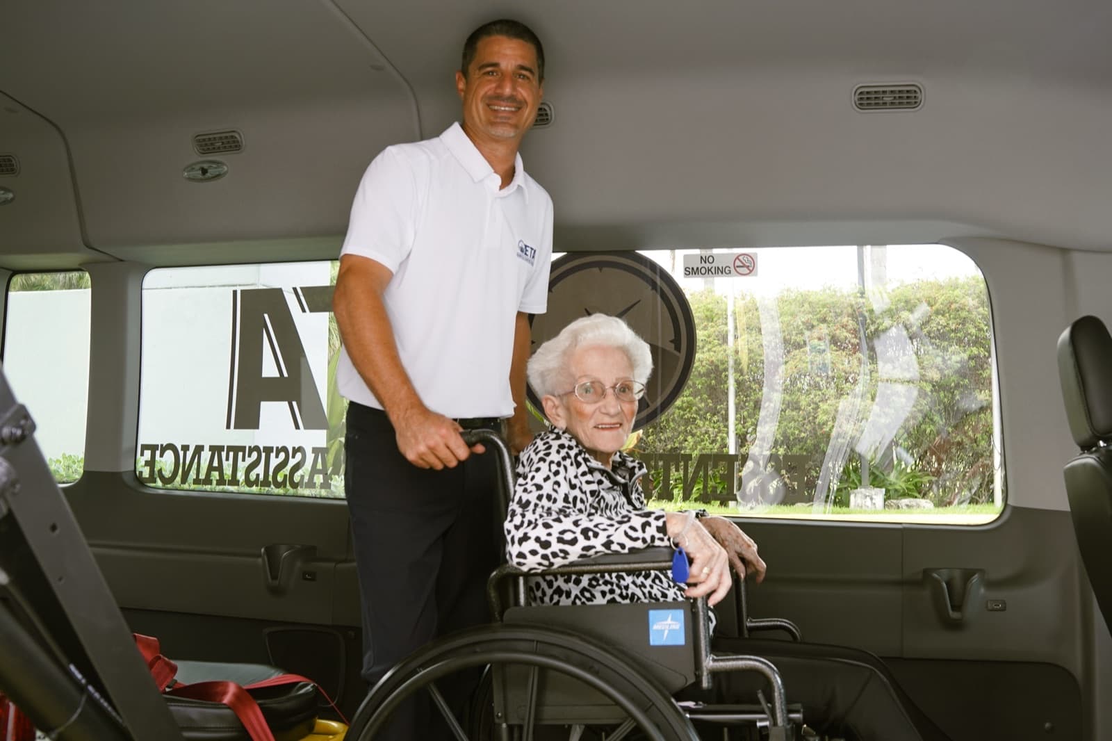 Essential Transport Assistance team member assisting a passenger in a wheelchair inside the medical transport van